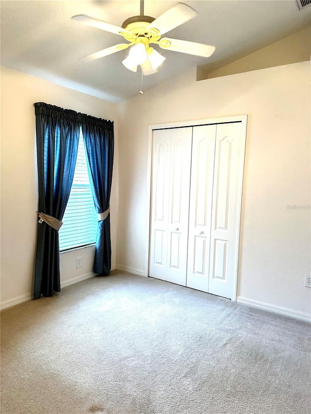 unfurnished bedroom with vaulted ceiling, carpet floors, ceiling fan, and a closet