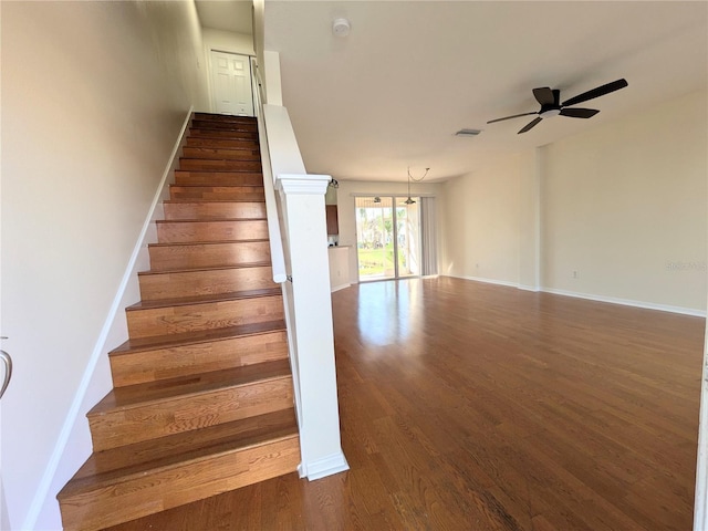 staircase featuring visible vents, ceiling fan, baseboards, and wood finished floors