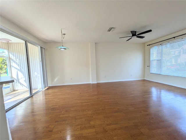 spare room with wood finished floors, visible vents, and baseboards