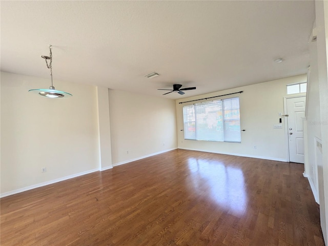 empty room featuring baseboards, ceiling fan, visible vents, and wood finished floors