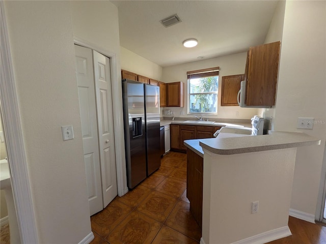 kitchen with stainless steel appliances, light countertops, visible vents, a sink, and a peninsula