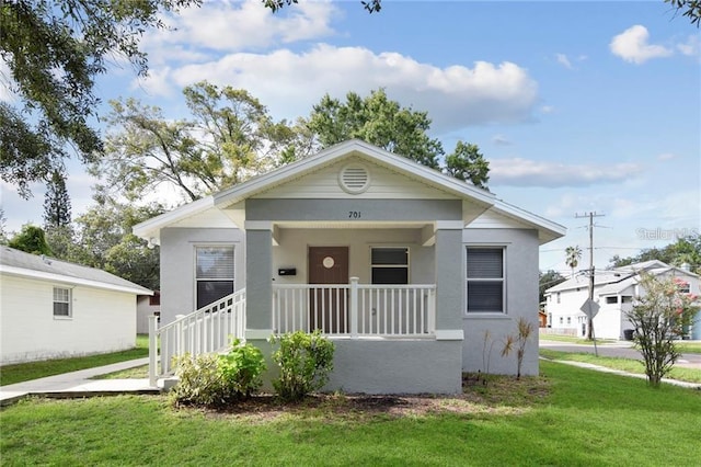 bungalow featuring covered porch and a front lawn