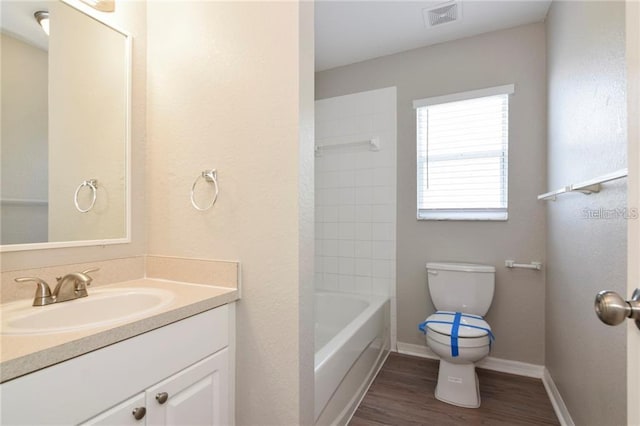 full bathroom featuring wood-type flooring, toilet, tiled shower / bath combo, and vanity