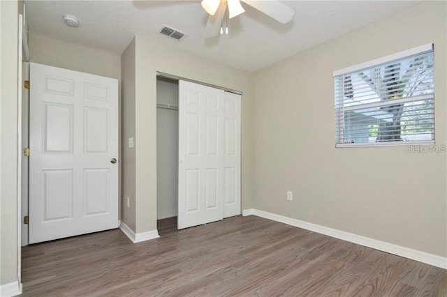 unfurnished bedroom with hardwood / wood-style flooring, a closet, and ceiling fan