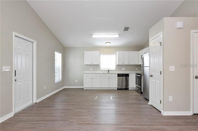 kitchen with stainless steel appliances, sink, white cabinets, and light hardwood / wood-style floors