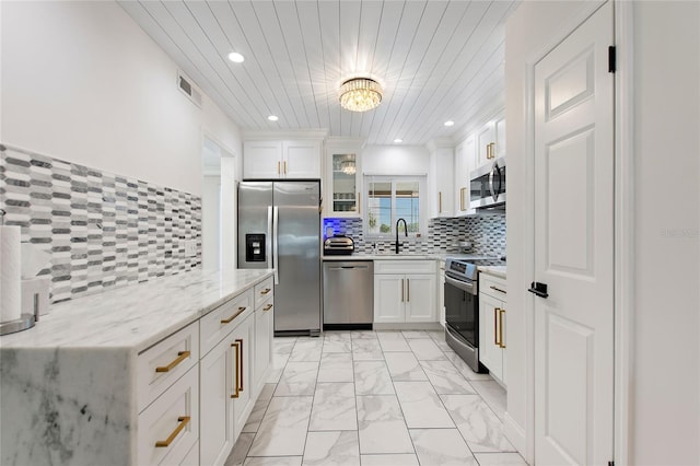 kitchen with white cabinetry, sink, backsplash, stainless steel appliances, and light stone countertops