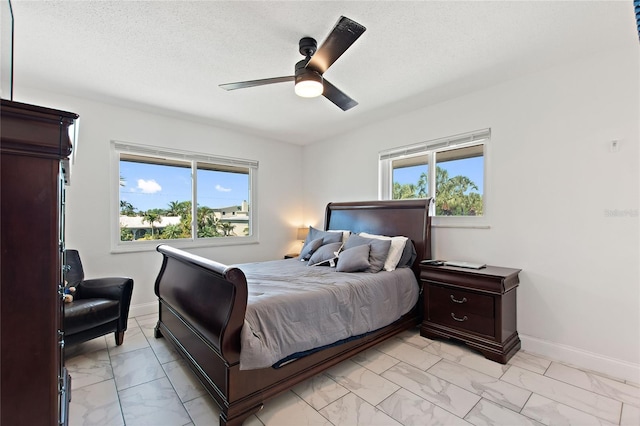 bedroom featuring multiple windows, ceiling fan, and a textured ceiling