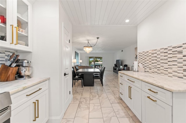 kitchen with white cabinets, tasteful backsplash, light stone countertops, and marble finish floor