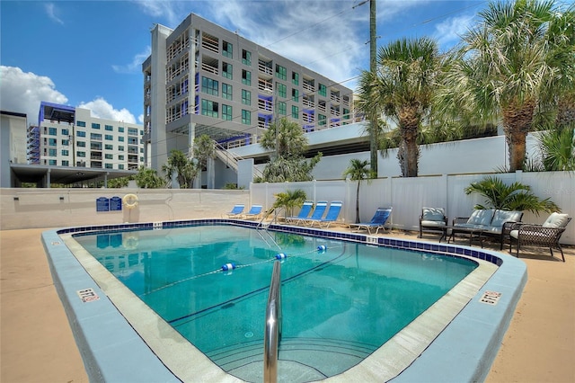pool with an outdoor hangout area and fence