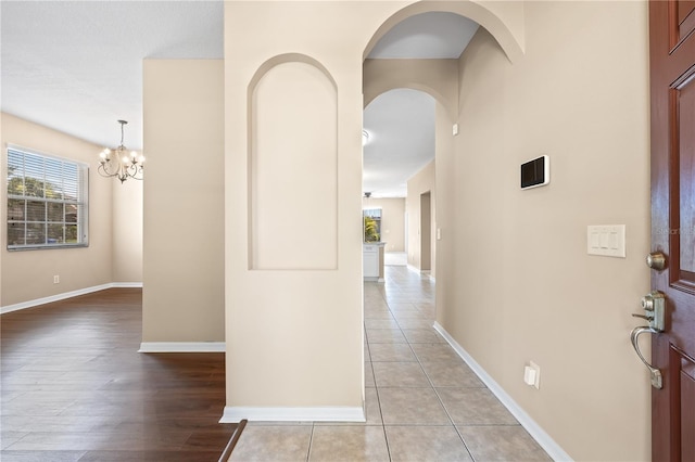 corridor featuring light tile patterned floors and a chandelier