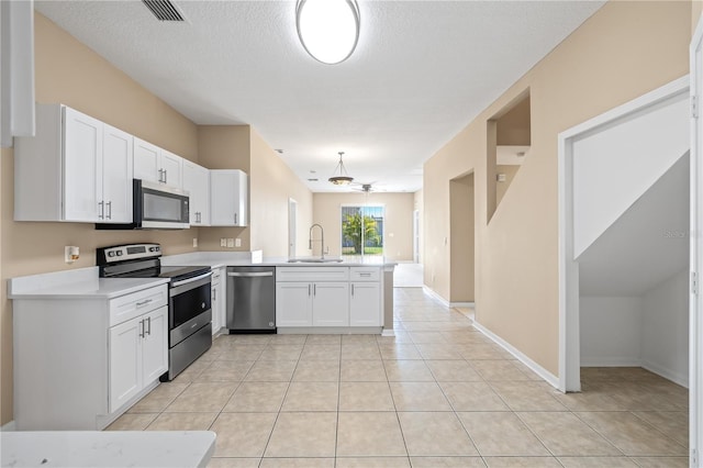 kitchen with sink, light tile patterned floors, appliances with stainless steel finishes, white cabinets, and kitchen peninsula