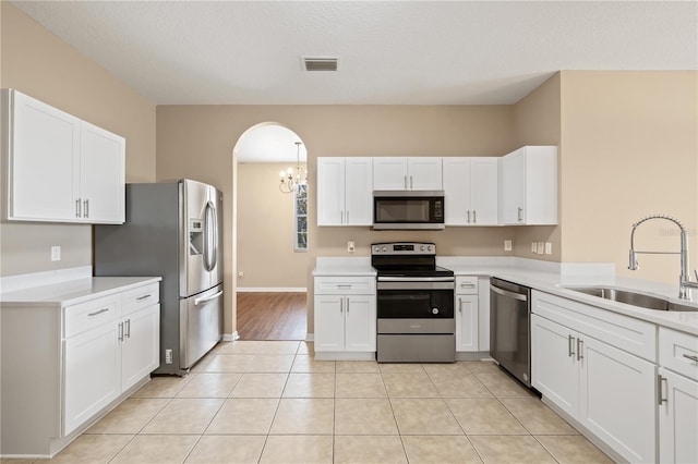 kitchen featuring white cabinetry, sink, light tile patterned floors, stainless steel appliances, and a textured ceiling