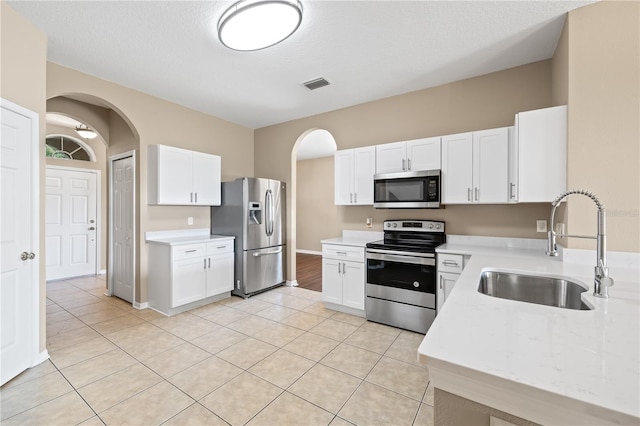 kitchen featuring white cabinetry, sink, stainless steel appliances, and light tile patterned flooring