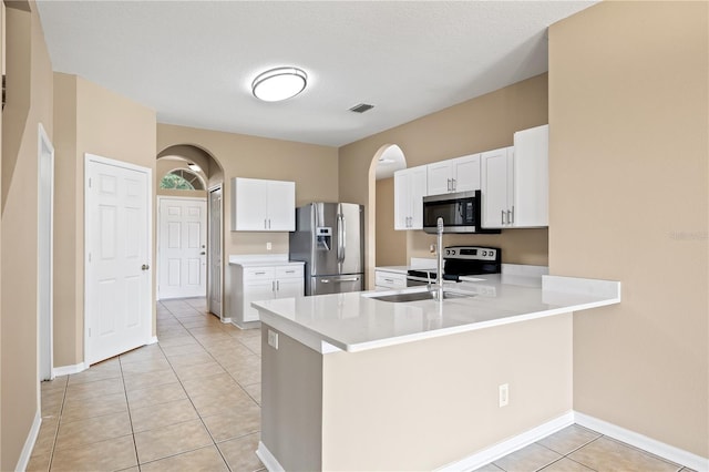 kitchen with appliances with stainless steel finishes, sink, white cabinets, light tile patterned floors, and kitchen peninsula