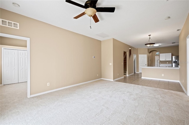 unfurnished living room with sink, light carpet, and ceiling fan