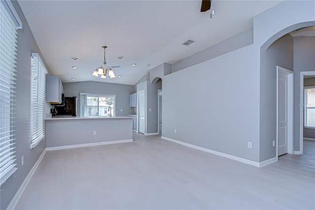 unfurnished living room with ceiling fan with notable chandelier, vaulted ceiling, and light hardwood / wood-style floors