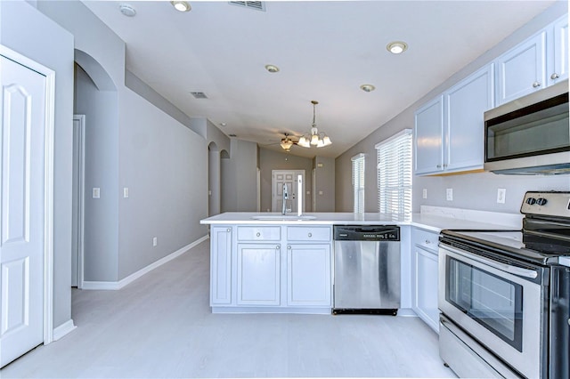 kitchen with sink, white cabinets, hanging light fixtures, kitchen peninsula, and stainless steel appliances