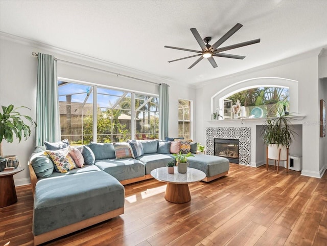 living room with a tile fireplace, hardwood / wood-style floors, and crown molding