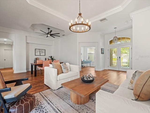 living room featuring french doors, ornamental molding, a raised ceiling, and hardwood / wood-style floors