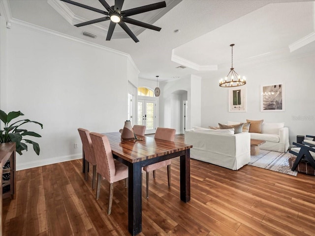 dining space with a raised ceiling, wood-type flooring, ornamental molding, and french doors