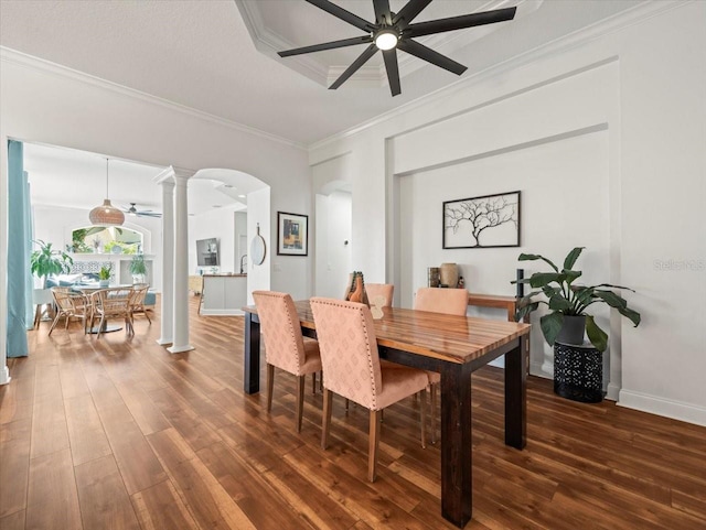 dining room featuring crown molding, dark wood-type flooring, ceiling fan, and ornate columns