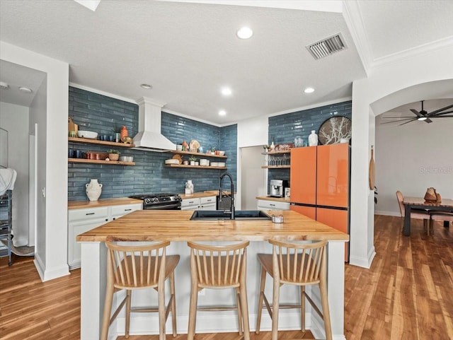 kitchen with wooden counters, a kitchen breakfast bar, sink, and white cabinets