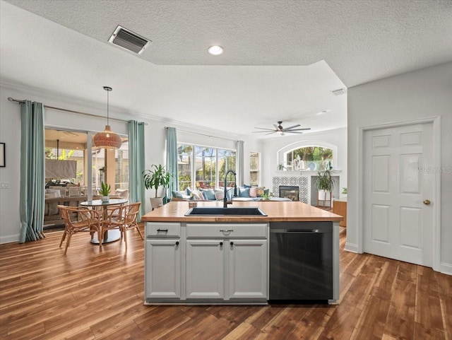 kitchen featuring dishwasher, sink, pendant lighting, and an island with sink