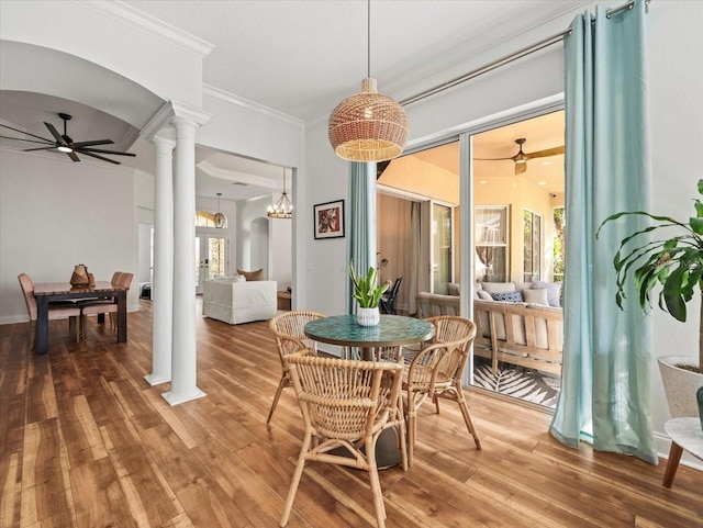 dining room featuring ornate columns, wood-type flooring, crown molding, and ceiling fan