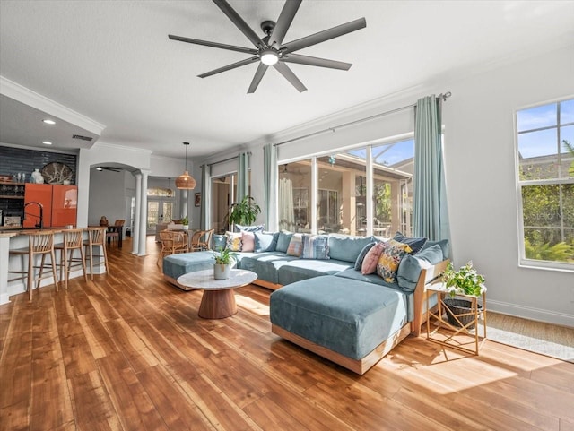 living room with decorative columns, hardwood / wood-style flooring, ornamental molding, ceiling fan, and a textured ceiling