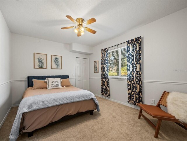 bedroom featuring ceiling fan, light colored carpet, a closet, and a textured ceiling