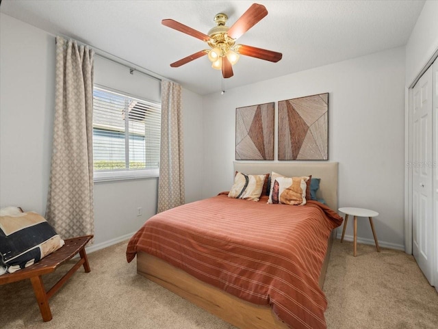 bedroom with ceiling fan, a closet, and light carpet