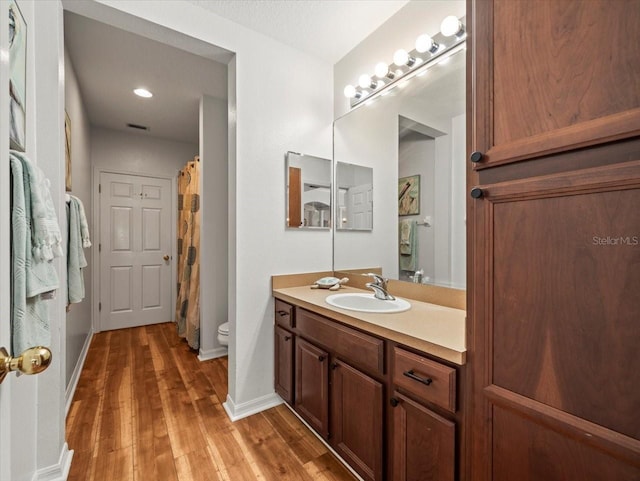 bathroom with wood-type flooring, vanity, and toilet