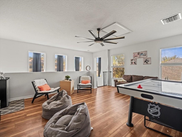 recreation room featuring a textured ceiling, wood-type flooring, and a healthy amount of sunlight