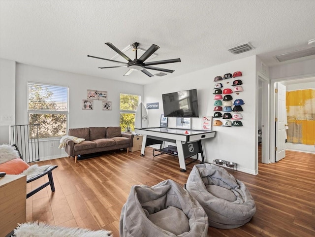 recreation room with ceiling fan, wood-type flooring, and a textured ceiling