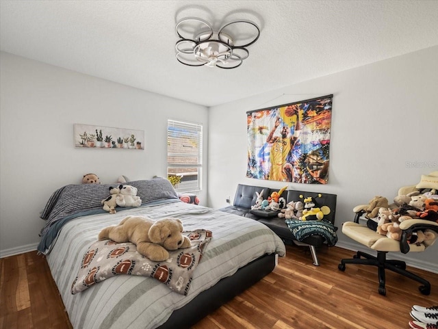 bedroom featuring an inviting chandelier, hardwood / wood-style flooring, and a textured ceiling