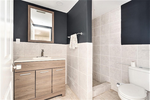 bathroom featuring tile walls, vanity, a shower, tile patterned floors, and toilet