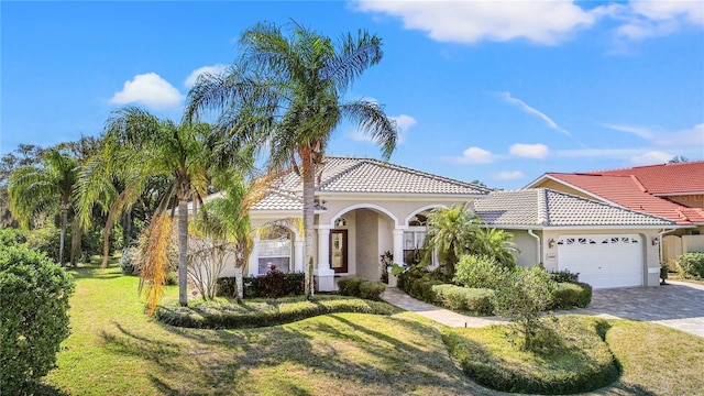 mediterranean / spanish-style house with a garage and a front lawn