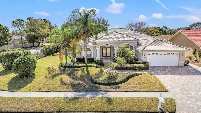 mediterranean / spanish-style house featuring a garage and a front lawn