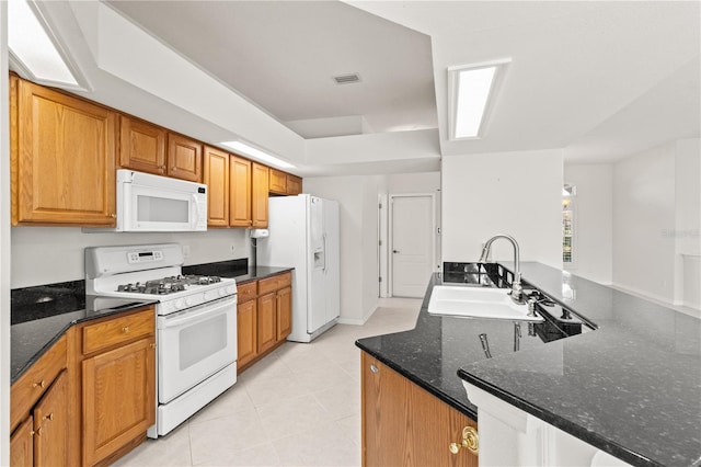 kitchen featuring light tile patterned flooring, sink, dark stone countertops, kitchen peninsula, and white appliances