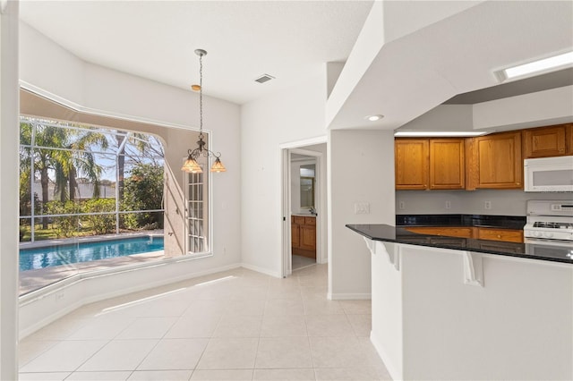 kitchen featuring light tile patterned flooring, a breakfast bar, decorative light fixtures, kitchen peninsula, and white appliances