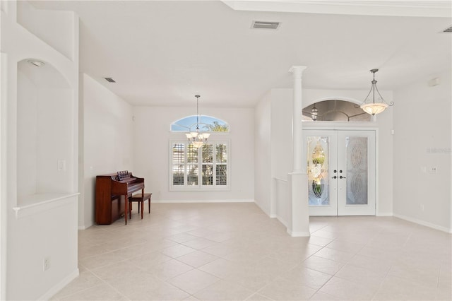 entrance foyer with french doors, a chandelier, light tile patterned flooring, and ornate columns