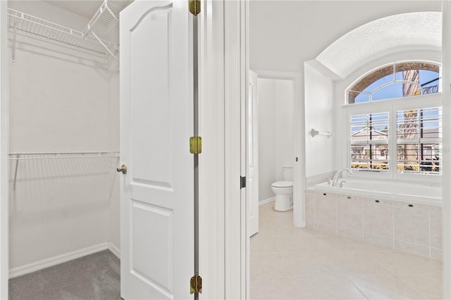 bathroom featuring toilet, tile patterned flooring, and tiled tub