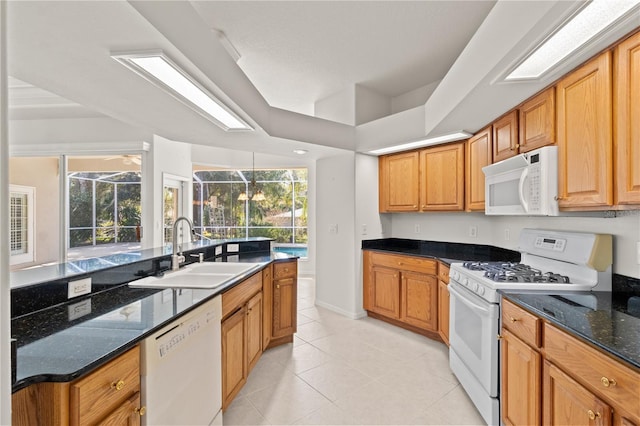 kitchen with dark stone countertops, sink, white appliances, and light tile patterned floors