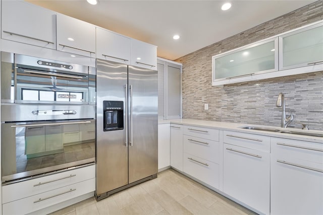 kitchen featuring stainless steel appliances, sink, white cabinets, and backsplash