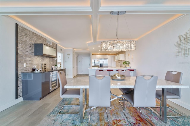 dining room with ornamental molding, sink, beverage cooler, and light wood-type flooring