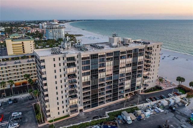 aerial view at dusk with a water view and a view of the beach