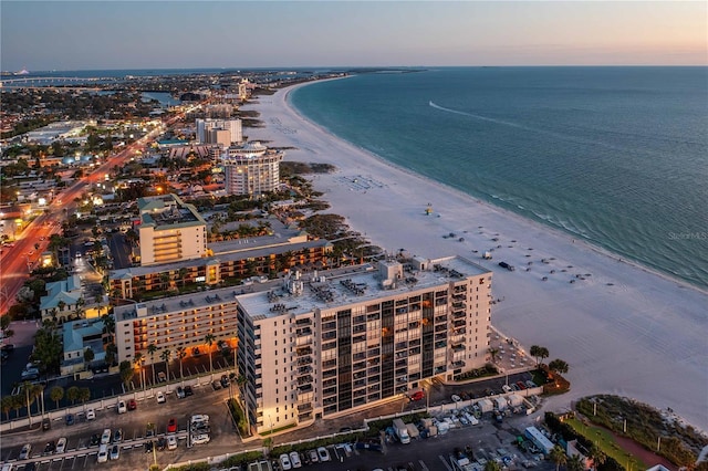 aerial view at dusk with a water view and a beach view