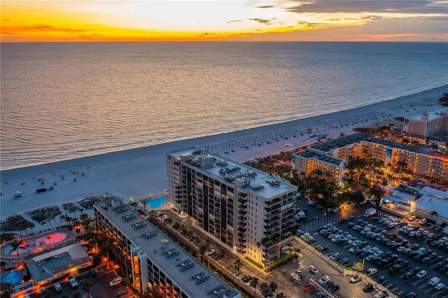 aerial view at dusk with a view of the beach and a water view