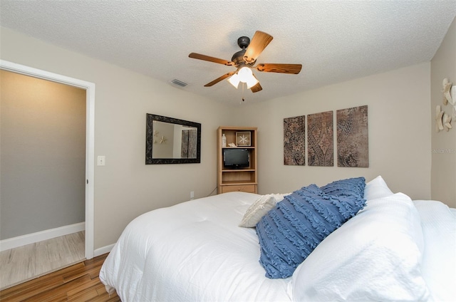 bedroom with baseboards, visible vents, wood finished floors, and a ceiling fan