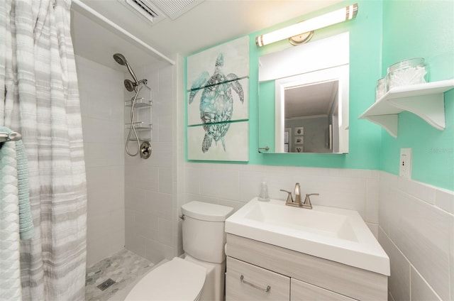 bathroom featuring tiled shower, tile walls, toilet, vanity, and visible vents